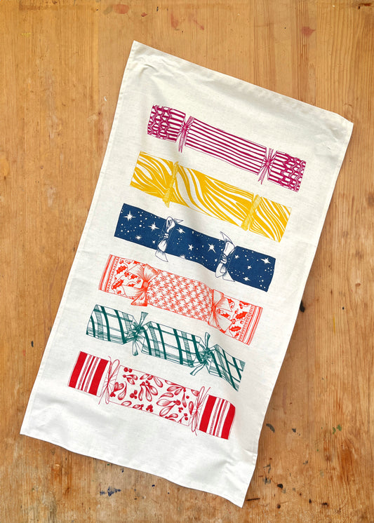 Lottie Day Christmas Cracker tea towel with festive screen-printed design on soft cotton – ideal for seasonal kitchen styling or gift wrapping