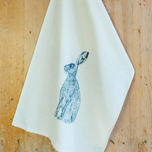 Blue Hare tea towel by Lottie Day – handmade cotton kitchen towel featuring moon-gazing hare illustration, inspired by Norfolk countryside
